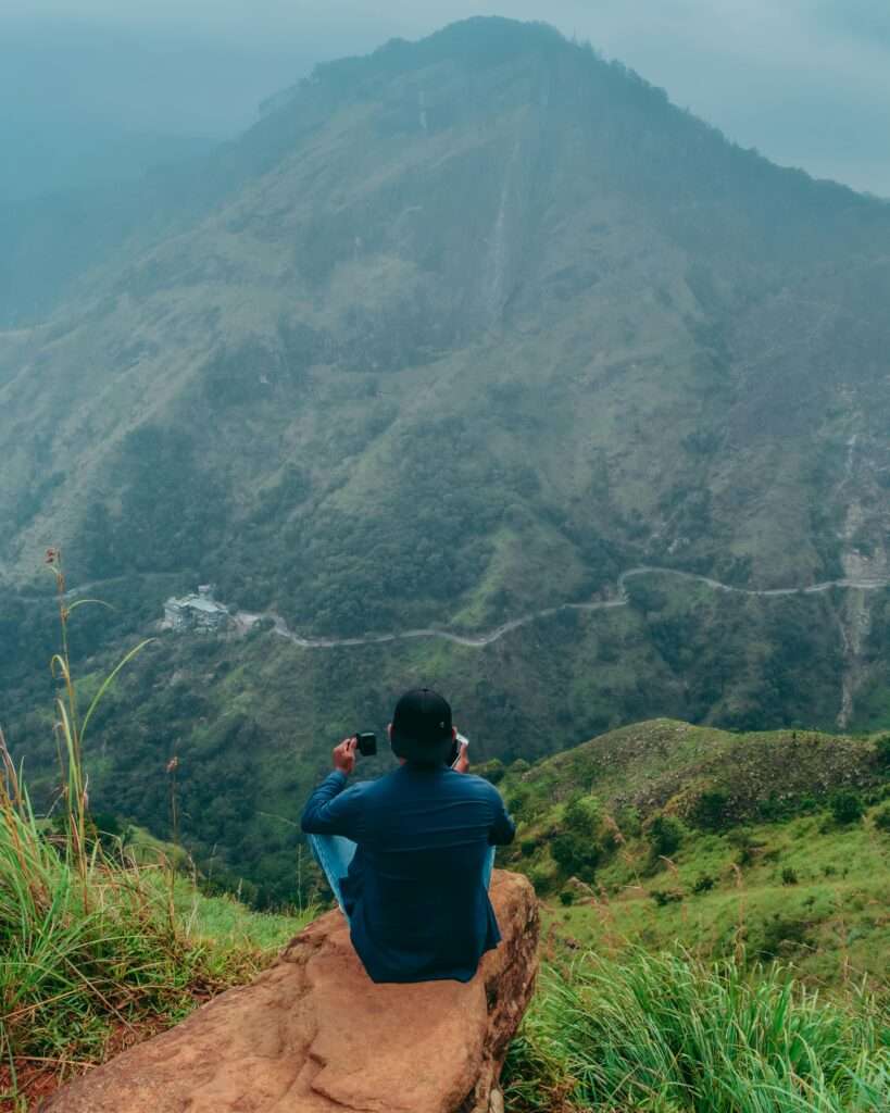 Man sitting on rock, capturing stunning Ella landscape in Sri Lanka. Perfect for travel and adventure themes.